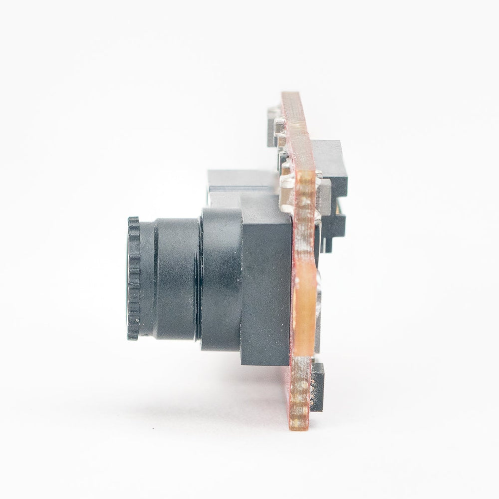 A small electronic component or sensor module with a dark gray cylindrical lens-like section and a copper-toned circuit board body, photographed on a seamless white background.