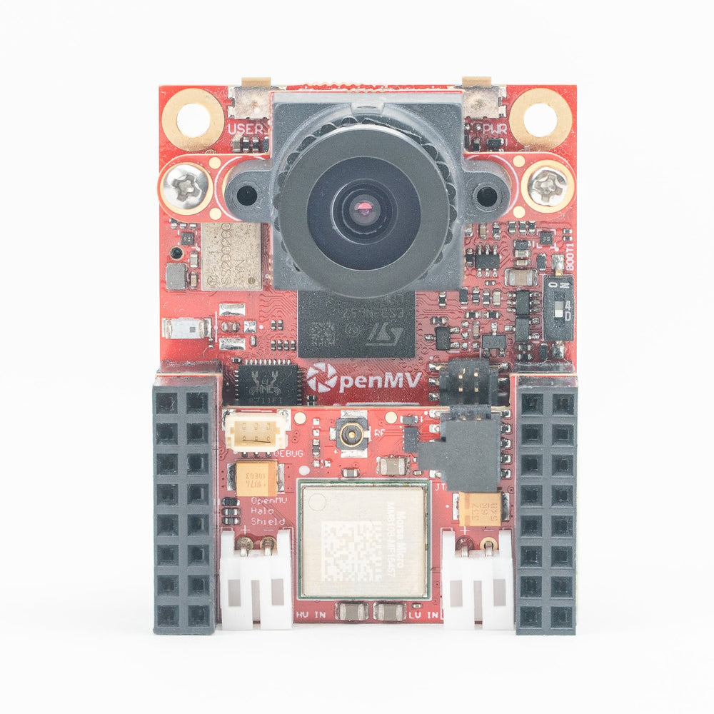 A red electronic circuit board with a central camera lens, two circular light indicators, a small white printed logo reading 'OpenMV', and gray connector blocks on the sides, photographed on a plain white background.